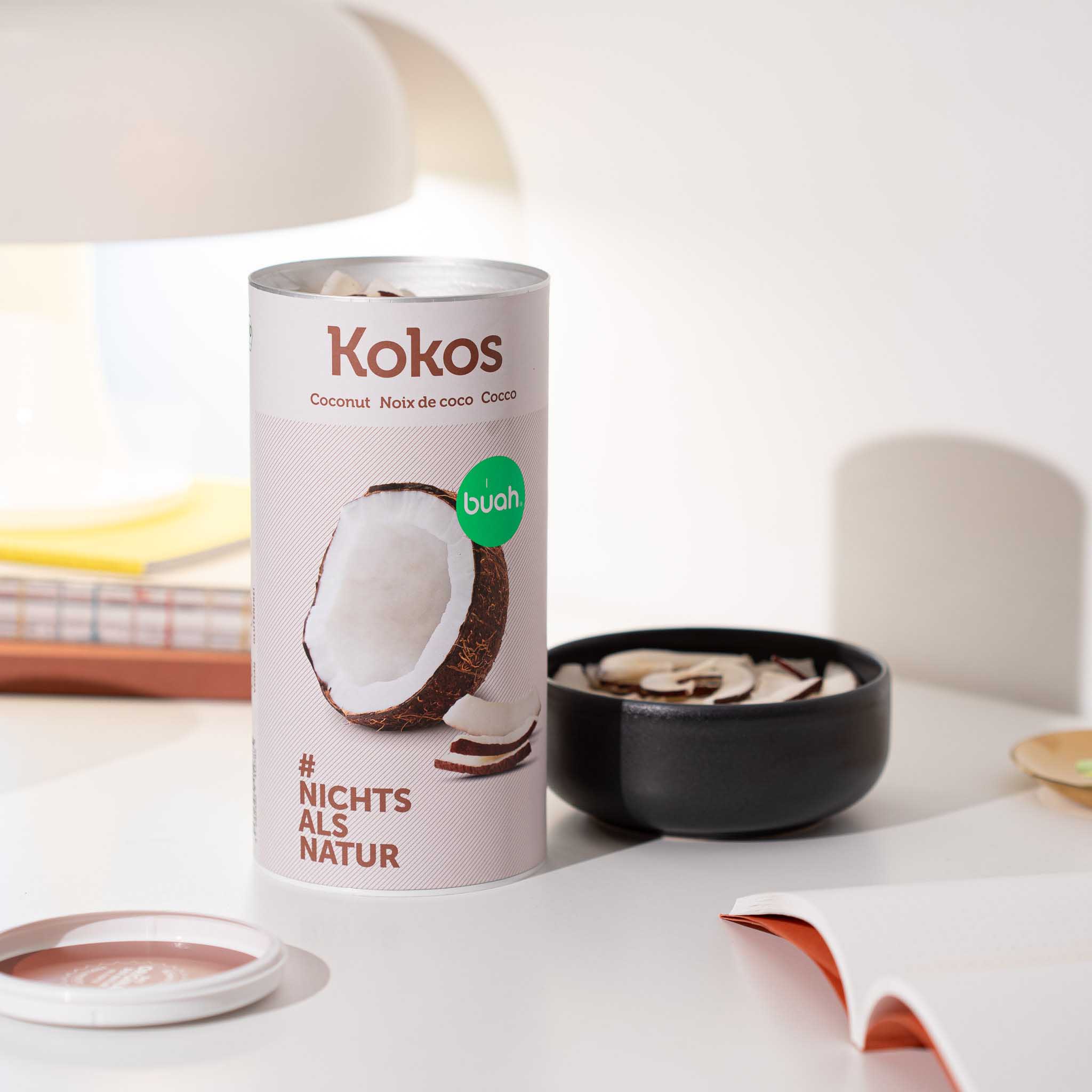 Dose buah Kokoschips auf Tisch neben Schale mit Kokoschips