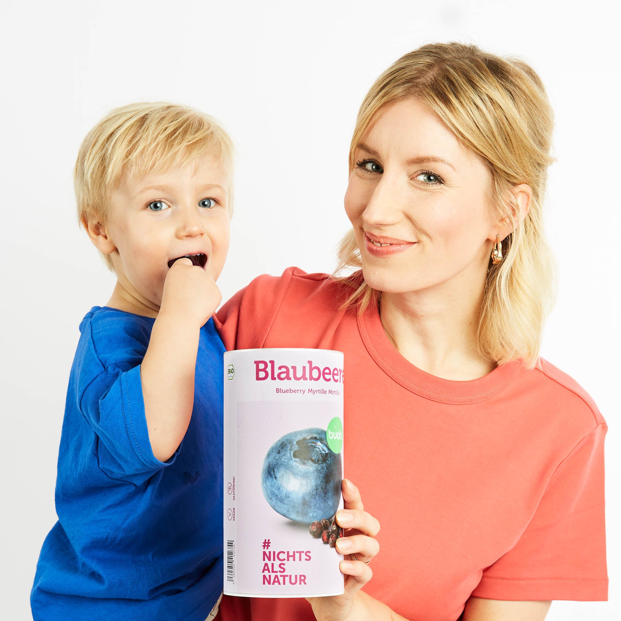 Mamma con il figlio in braccio e una lattina di mirtilli buah in mano