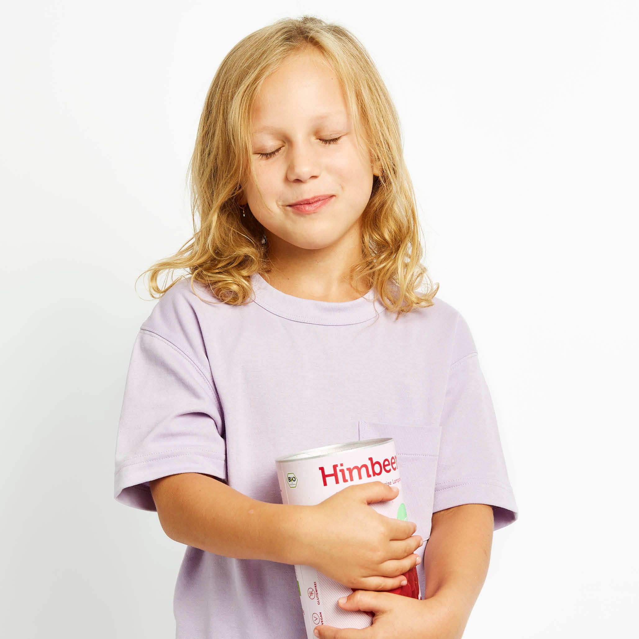 Kind mit geschlossenen Augen hat eine Dose buah Himbeeren in der Hand und lacht