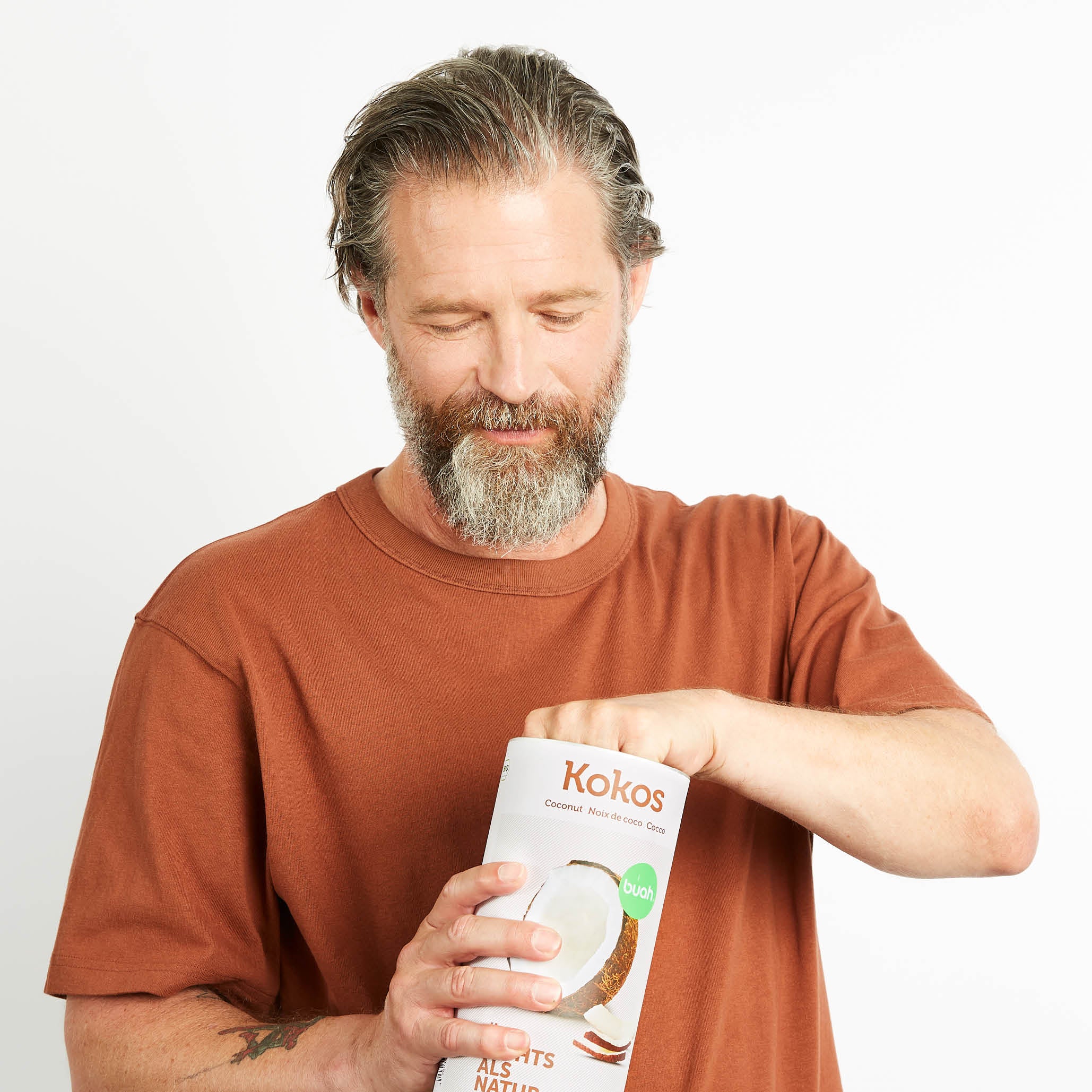 Mann in braunem Shirt nimmt buah Kokoschips aus einer Dose Kokoschips