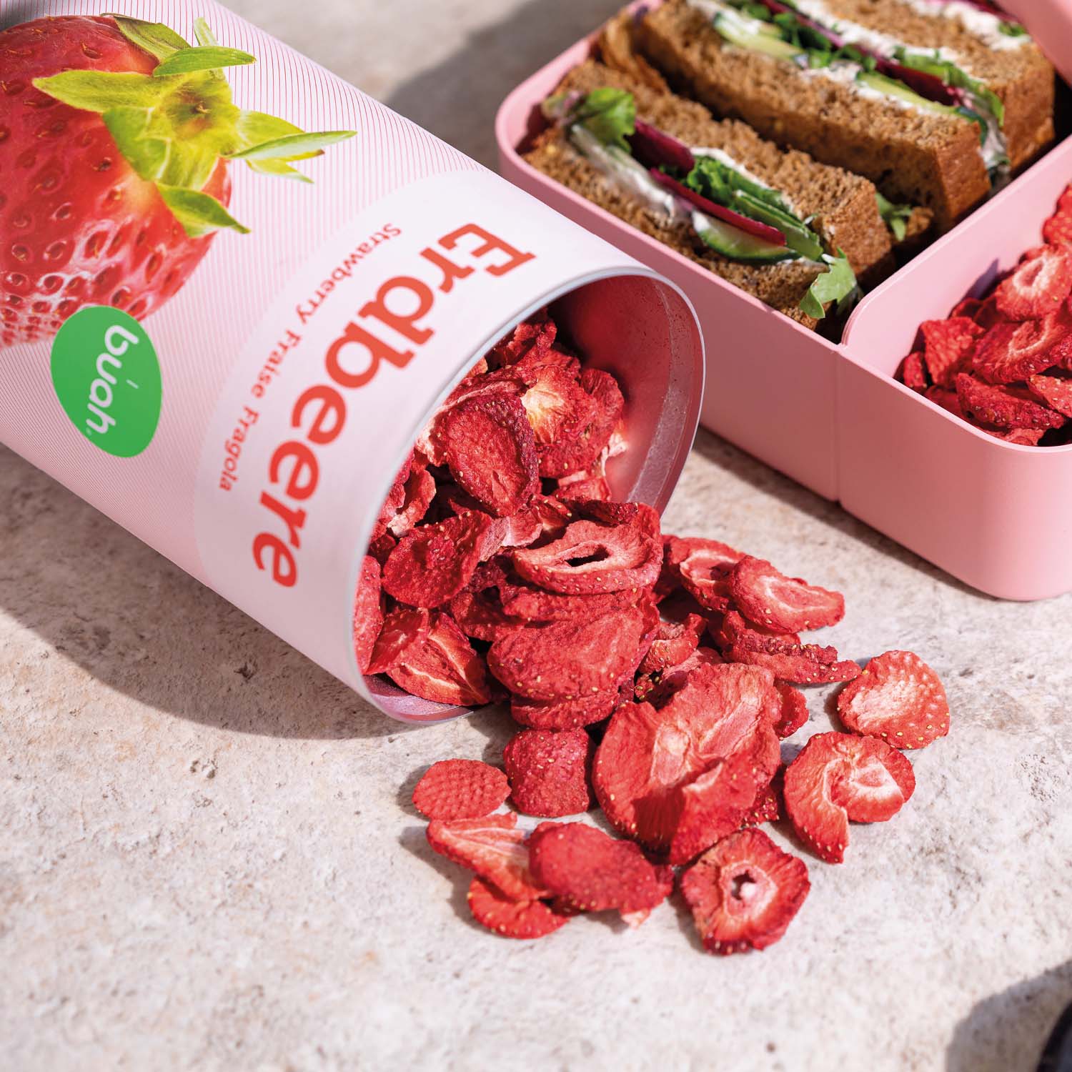 buah gefriergetrocknete Erdbeeren fallen aus liegender Dose Erdbeeren neben einer Brotzeitbox