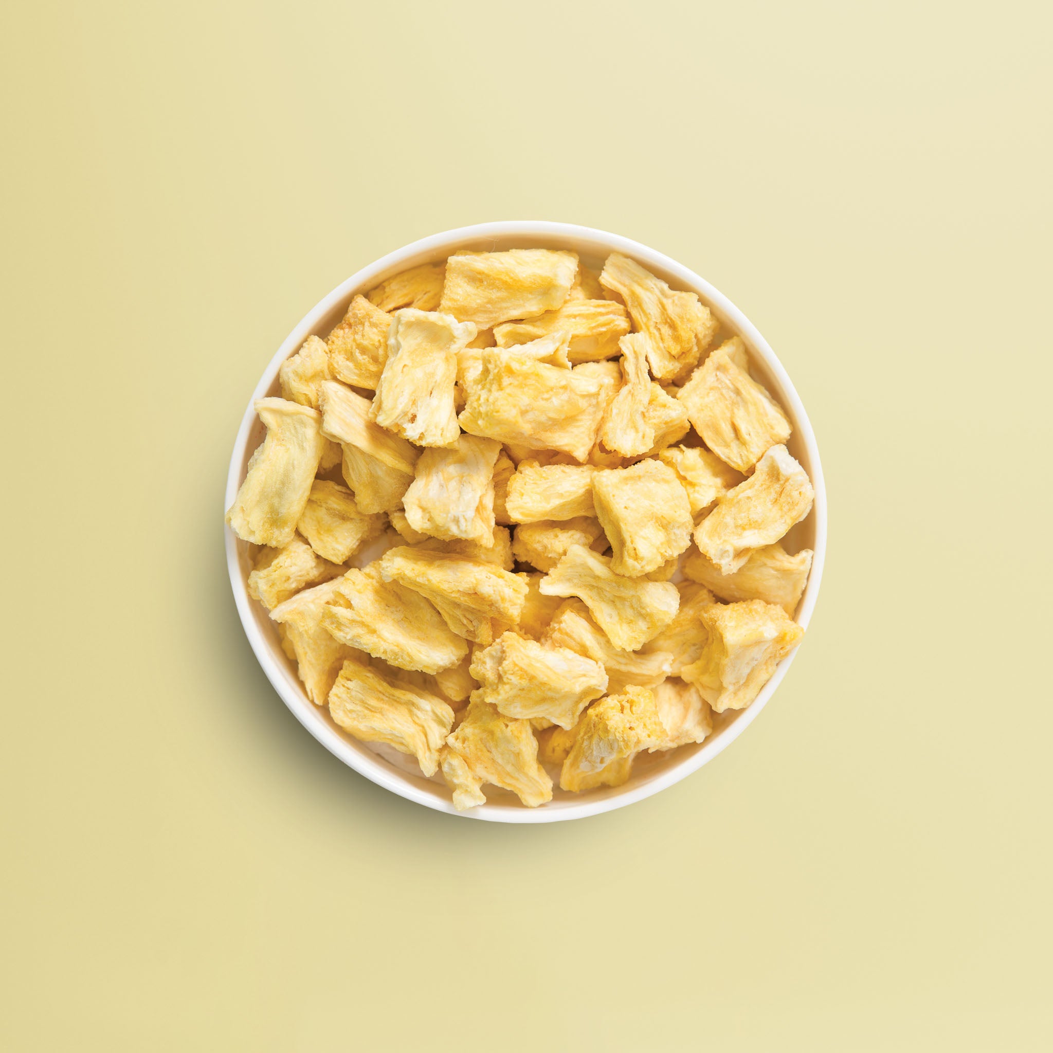 Viele gelbe, knackige und gefriergetrocknete Ananas Stuecke von buah in einer Schale