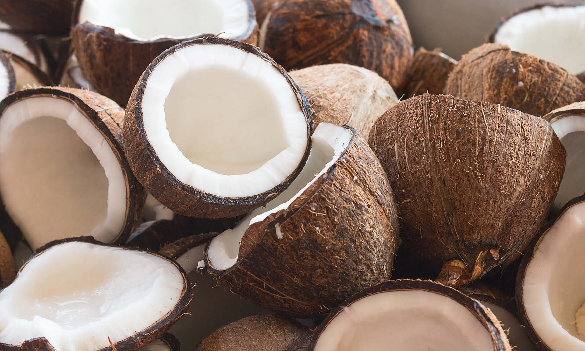 Viele halbierte Kokosnuesse liegen auf und nebeneinander