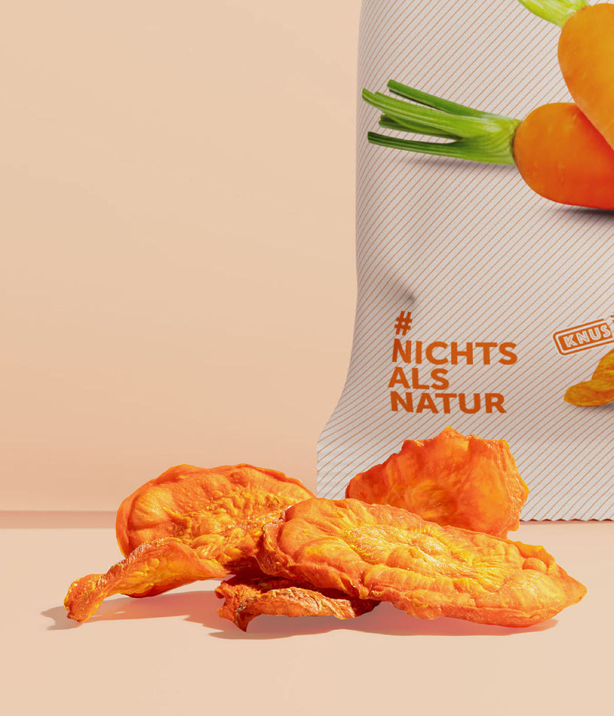 Kleiner Haufen vakuumgetrocknete Karottenchips von buah vor einer Packung Karottenchips