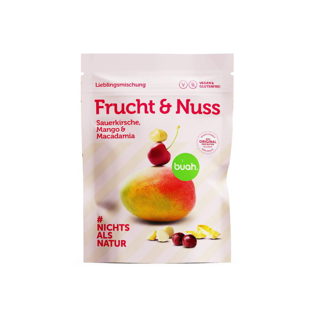 Neue buah Frucht & Nuss Mischung mit gefriergetrockneter Sauerkirsche, Mango und Macadamia Nuss vor rosa Hintergrund und Fruchthaufen vor der Packung.