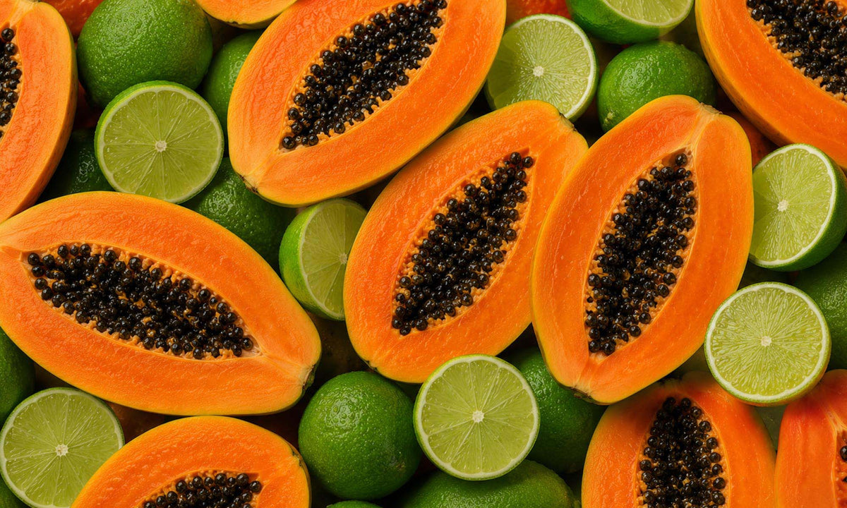 Aufgeschnittene Papayas und halbierte Limetten liegen dicht an dicht in einer farbintensiven Draufsicht.