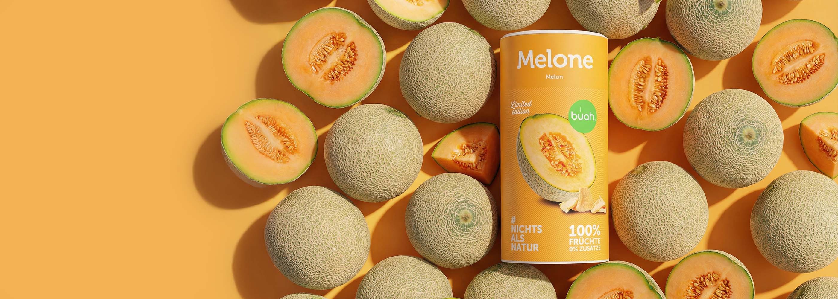 Viele frische Cantaloupe Melonen liegen vor einem orangenen Hintergrund, manche aufgeschnitten. In der Mitte buah Dose gefriergetrocknete Cantaloupe Melone ebenfalls in Orange.