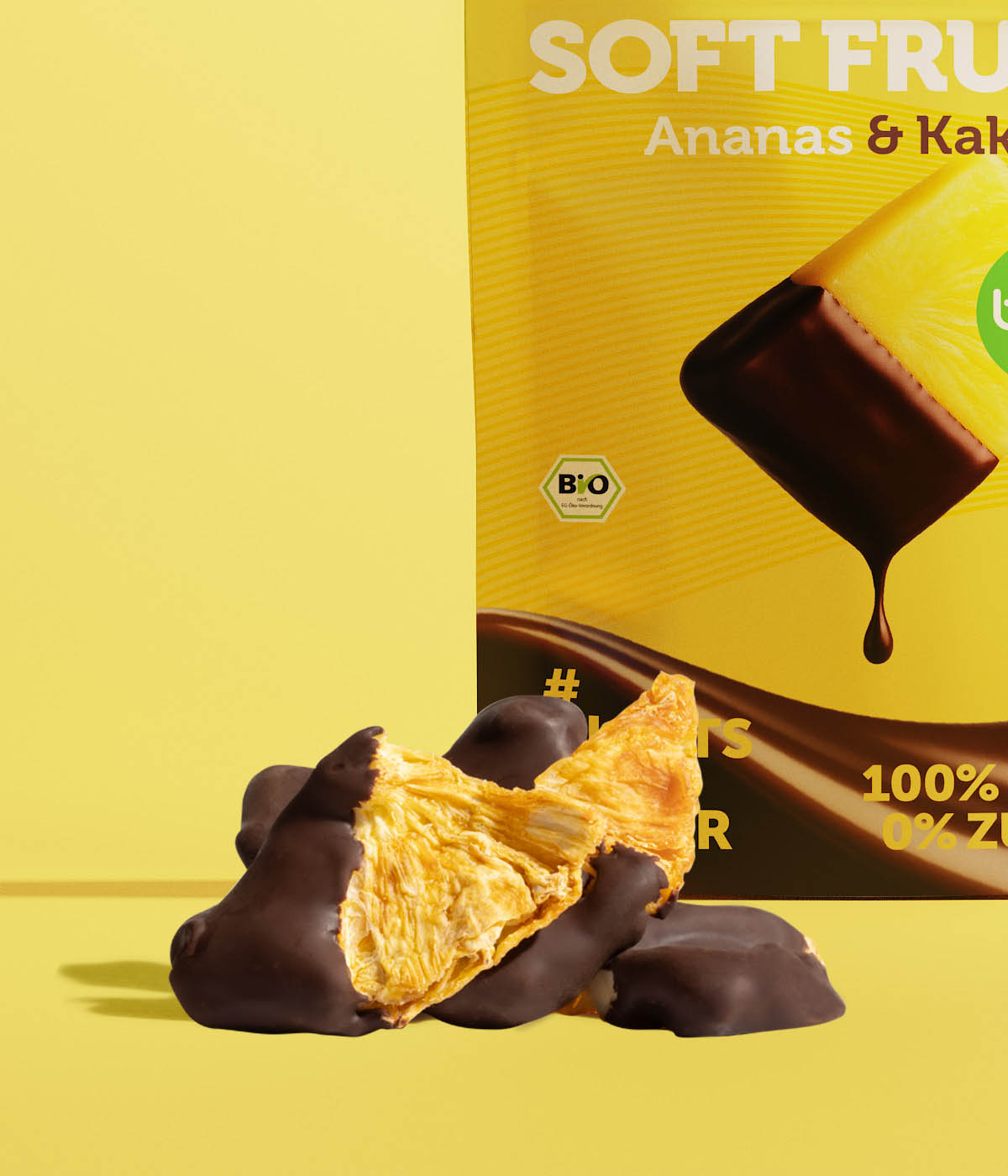 Getrocknete Bio-Ananasstücke mit dunklem Kakaomantel vor der buah Soft Fruits Ananas & Kakao Verpackung