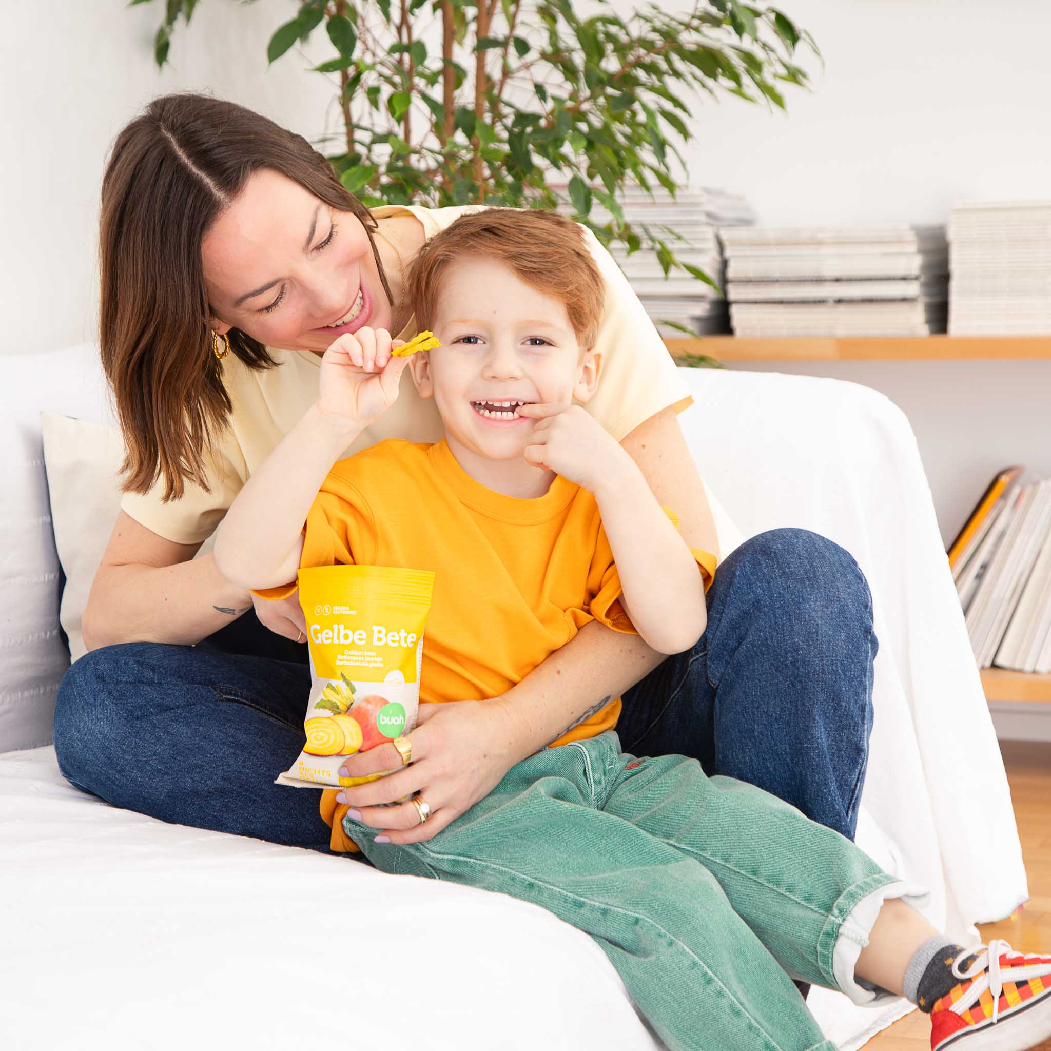 Mama und Sohn auf einem Sofa essen Gelbe Bete buah Chips