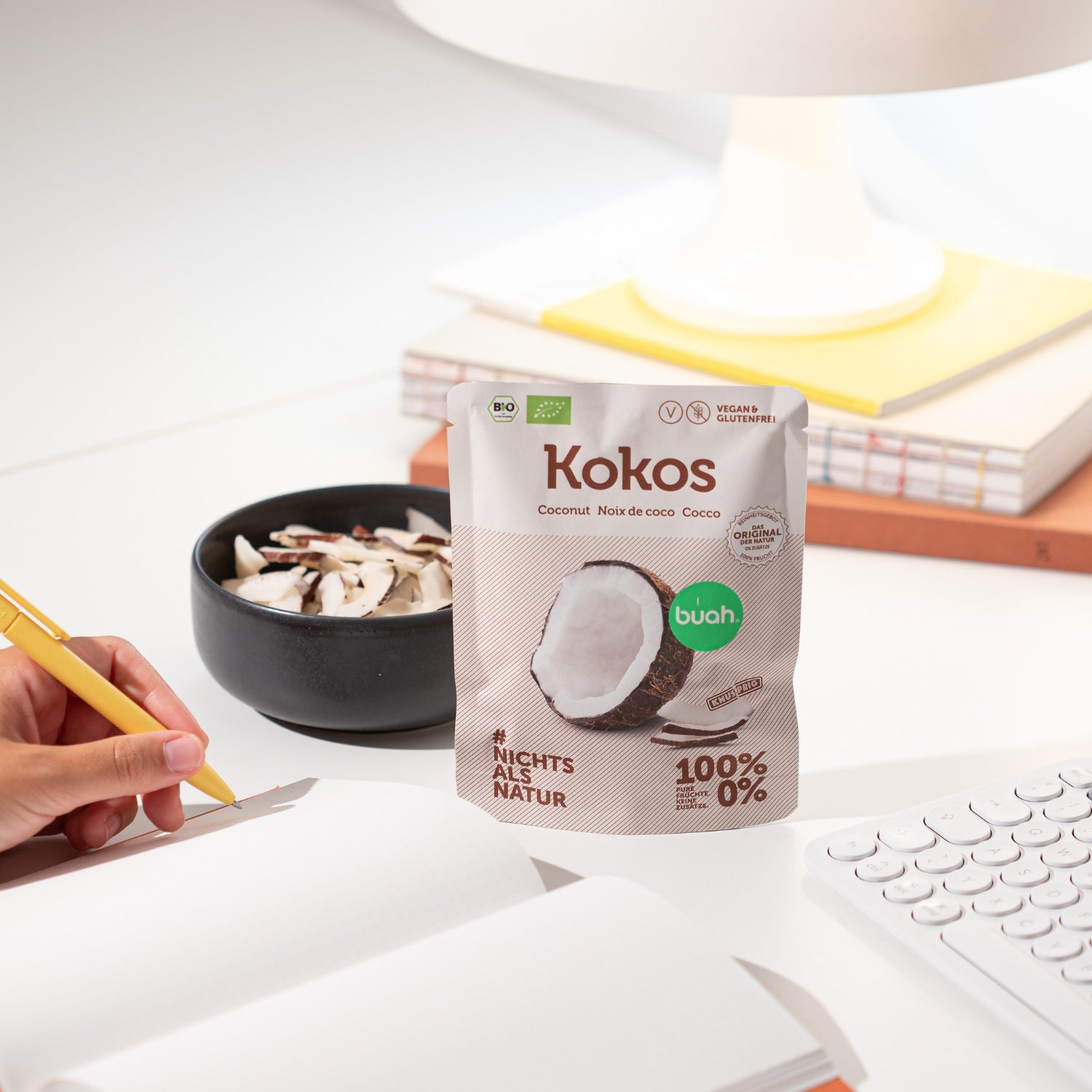 Snackpack buah Kokoschips auf einem Schreibtisch neben einer Schale Kokoschips