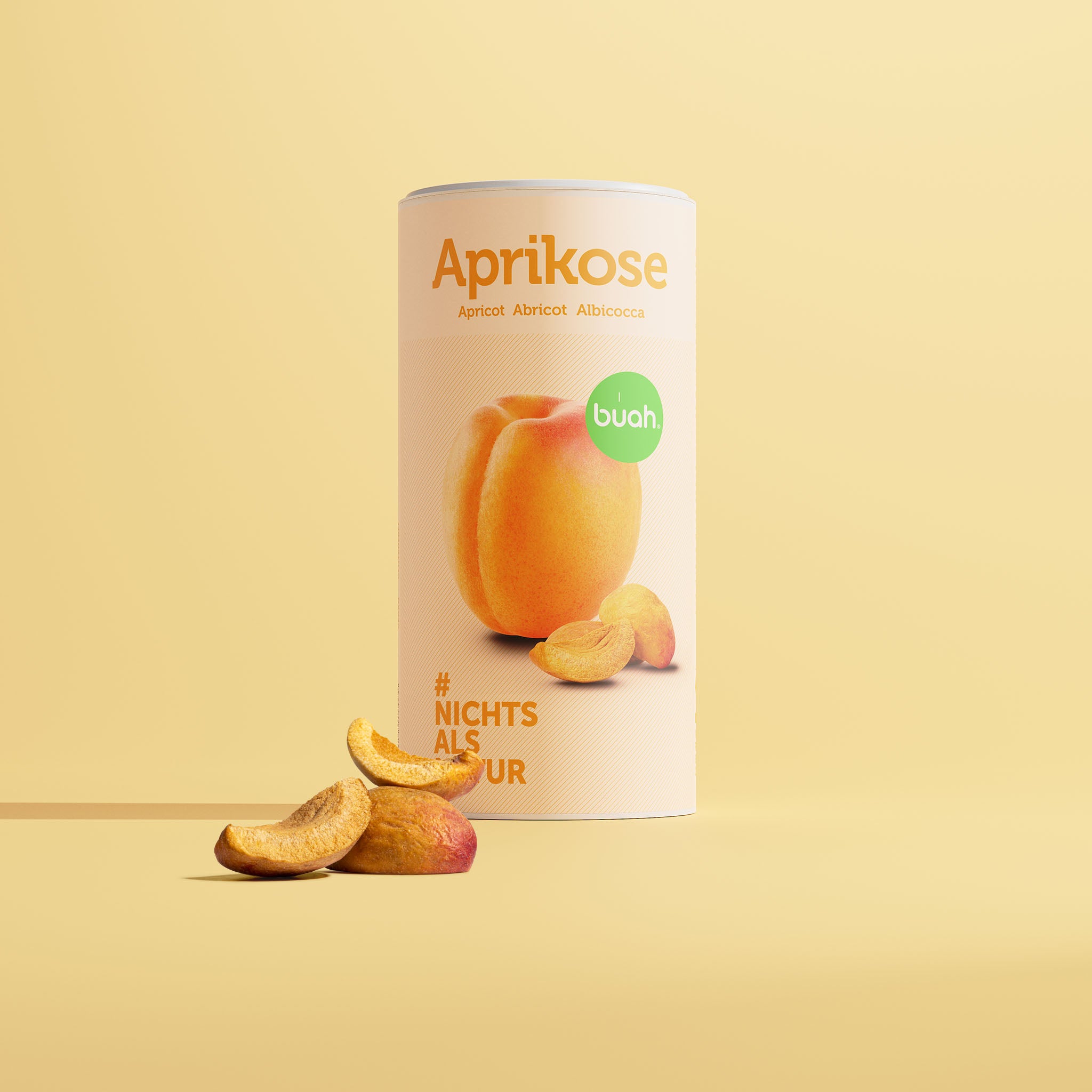 buah albicocca liofilizzata in un barattolo grande con intagli di albicocca davanti al barattolo e uno sfondo giallo 